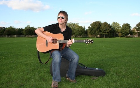 Cliff Smith Guitar Lessons - Cliff playing acoustic guitar in a field